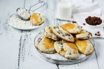 Concept of Russian cuisine. Sochniki with cottage cheese and raisins. Bakery products. Shortbread dough with sweet cottage cheese on a white wooden background. Background image, copy space