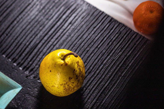 Fresh raw green yellow pear and mandarin still life on black white and blue background.