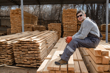 Portrait of young man carpenter at the wooden warehouse is resting
