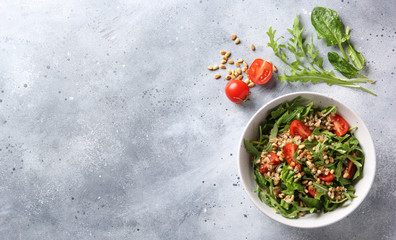 The concept of healthy food. Leaf salad with grits and pine nuts in a deep bowl. Arugula, spinach,...
