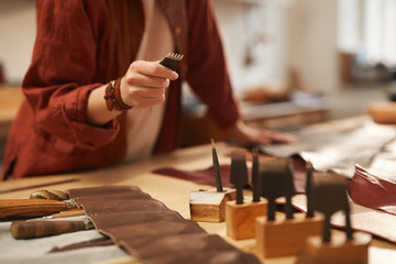 Unrecognizable craftswoman choosing right tool for further work with leather, horizontal shot