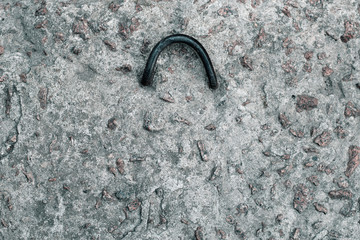 Dirty concrete surface with a metal loop for lifting. Gray concrete texture
