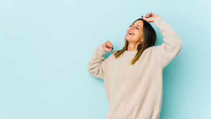 Young woman isolated on blue background celebrating a special day, jumps and raise arms with energy.