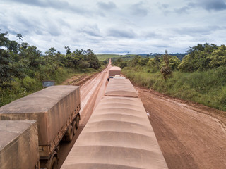 Obraz premium Drone aerial view of trucks transporting soybeans, driving along the BR 163 road near Novo Progresso city in the Amazon. Rainforest area and deforestation in the background. BR-163, Para, Brazil.