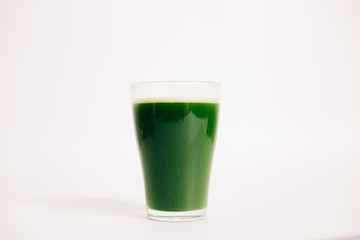 green freshly squeezed juice of green Apple and young spinach leaves on a white background