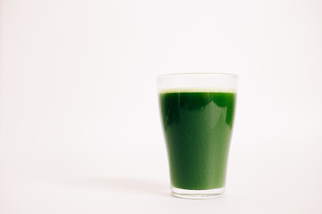 green freshly squeezed juice of green Apple and young spinach leaves on a white background