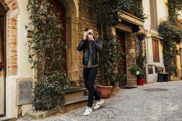 Fototapeta na wymiar Photographer in action. Tourist man taking photo on his camera. Photographer make a photo on a cozy street in Italy.