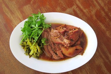 Stewed pork leg with green kale on white plate. Thai style food.