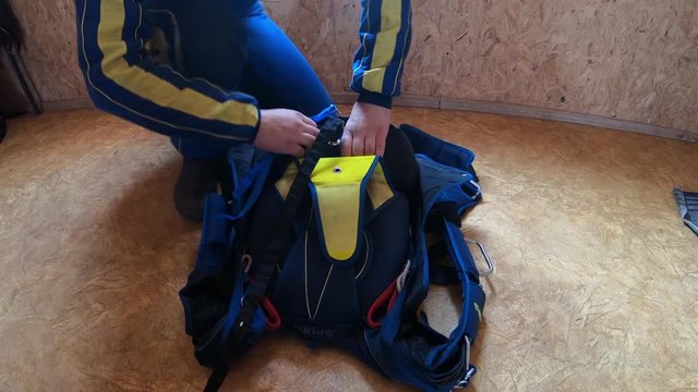 A man packs a blue sports parachute with his hands and feet in the frame