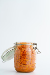 500 grams of spicy korean carrot salad with oil, garlic and black pepper in glass jar. Sustainable packaging, white background, high resolution