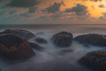 sunrise on beach rocks.