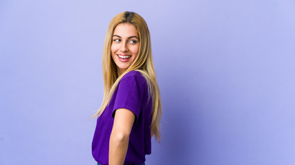 Young blonde woman isolated on purple background confident keeping hands on hips.