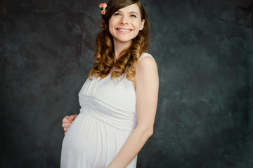 Fototapeta na wymiar Happy pregnant caucasian young woman on dark backdrop. Maternity, femininity, mother's day concept.