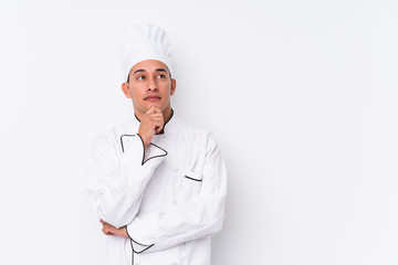 Young latin chef man isolated looking sideways with doubtful and skeptical expression.