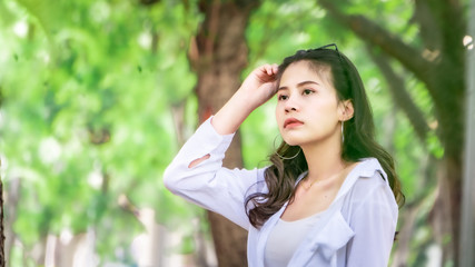 Beautiful Asian women with long hair wearing a white shirt. White bug hat, jeans showing emotions In the nature park