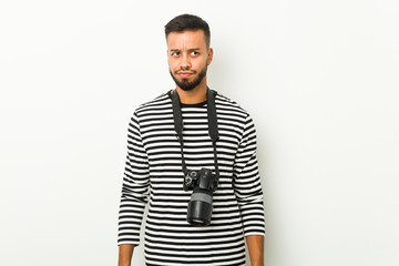 Young south-asian photographer confused, feels doubtful and unsure.
