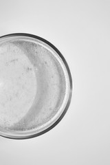 Close-up transparent shower gel in glass petri dish on white background. Cosmetic texture, above