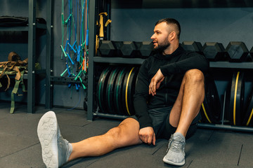 Fitness man sits on the floor and looking away or relaxing. Fitness, sport, exercising and diet concept.