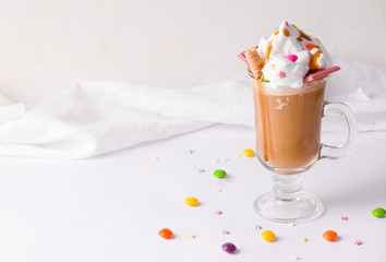 cold coffee with ice cream, whipped cream decorated with multi-colored sweets on a white background. copy space