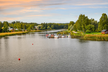 Fototapeta premium A colorful sky as the sun sets over boats, dock, homes and a park along the Porvoonjoki River in Porvoo, Finland.