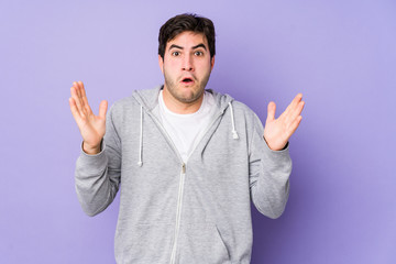 Naklejka premium Young man isolated on purple background celebrating a victory or success, he is surprised and shocked.