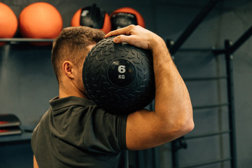 Muscular athletic man exercise with medicine ball at health club or gym. Fitness routine with exercise ball to maintain the abs. Sport, exercising, training and lifestyle concept.
