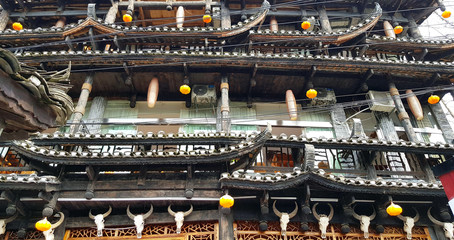 wooden house, in the style of Chinese ancient style. balcony and many elements of the tiled roof. nailed skulls of cows on the wall