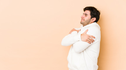 Young man isolated on beige background hugs, smiling carefree and happy.