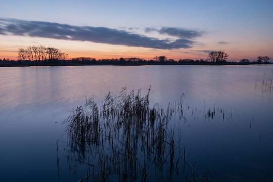 Lake and sky evening view after sunset, long exposure and blurry reeds by the wind