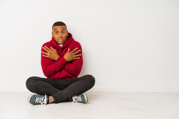 Young latin man sitting on the floor isolated going cold due to low temperature or a sickness.