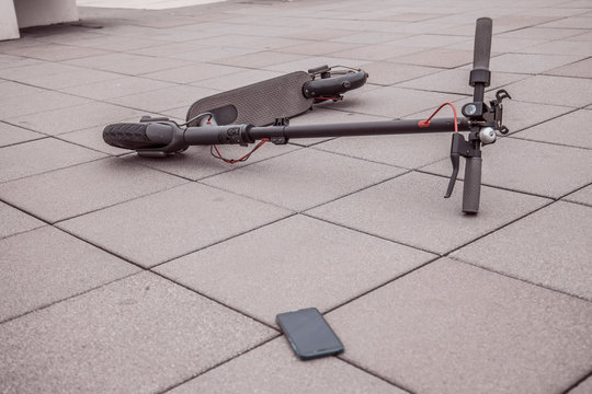 accident situation with electric scooter and smart phone on sidewalk