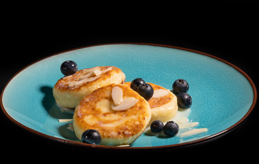 Cheese pancake with almonds and blueberries poured with condensed milk on a blue plate