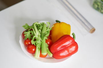 Woman using food film for food storage on a white table. Roll of transparent polyethylene food film for packing products.