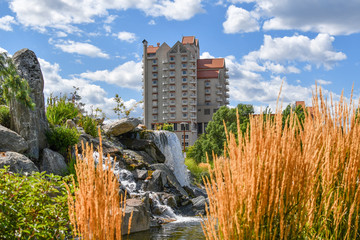 A tourist resort hotel in Coeur d'Alene Idaho rises above the memorial waterfall and pond in McEuen...