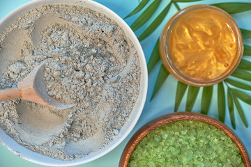 spa massage clay powder, face masks, bath salt, towel, shea butter on blue table background.