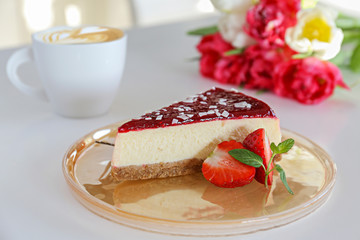 Delicious healthy vegetarian food, organic strawberry cheesecake slice, fresh red berries, green mint leaves, bouquet of different tulips and cup of cappuccino on white table. Close up, top front view