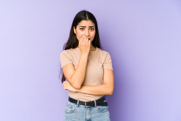 Young indian woman isolated on purple background biting fingernails, nervous and very anxious.