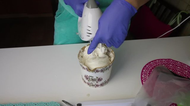 A man adds stewpan syrup to a container. Woman using a blender mixes marshmallow and syrup in a container.