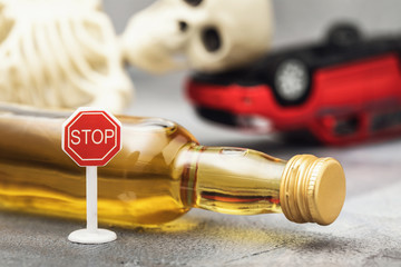 Road sign, a bottle of whiskey, a skeleton and an inverted car. Concept on the topic of drunk driver