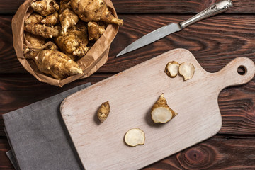 Several Jerusalem artichoke tubers in a paper bag on a wooden table with copy space. Helianthus tuberosus. Top view