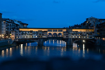 Ponte Vecchio in Florence by day, with the lights reflecting in the water