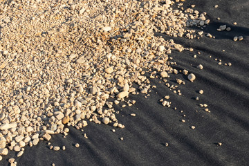 Spreading river pebble over the laid woven geotextile fabric in the summer garden under...