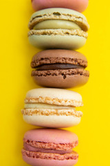 Colorful abstract background with traditional french macaroons cookies, over yellow background with copy space.