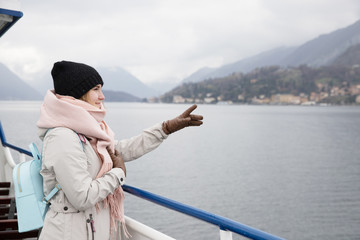 Portrait woman tourist passage cruise in fjords Scandinavian. Hat, scarf and backpack. Looks into distance mountains in fog