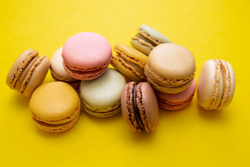 Colorful macaroons cookies, over yellow background with copy space. Traditional french dessert, abstract background.