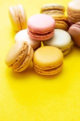 Colorful macaroons cookies, over yellow background with copy space. Traditional french dessert, abstract background.