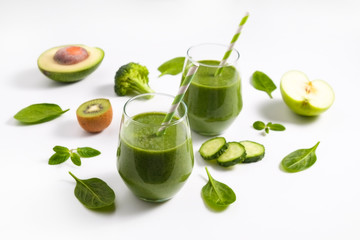 Freshly made green smoothie made of vegetables, fruits, herbs and greens. Glass of blended vegan beverage with ingredients around. Top view, close up, copy space, background.
