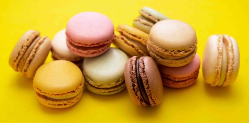 Colorful abstract background with traditional french macaroons cookies, over yellow banner.