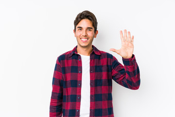 Young caucasian man posing in a pink background isolated smiling cheerful showing number five with fingers.