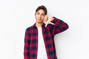 Young caucasian man posing in a pink background isolated showing a dislike gesture, thumbs down....